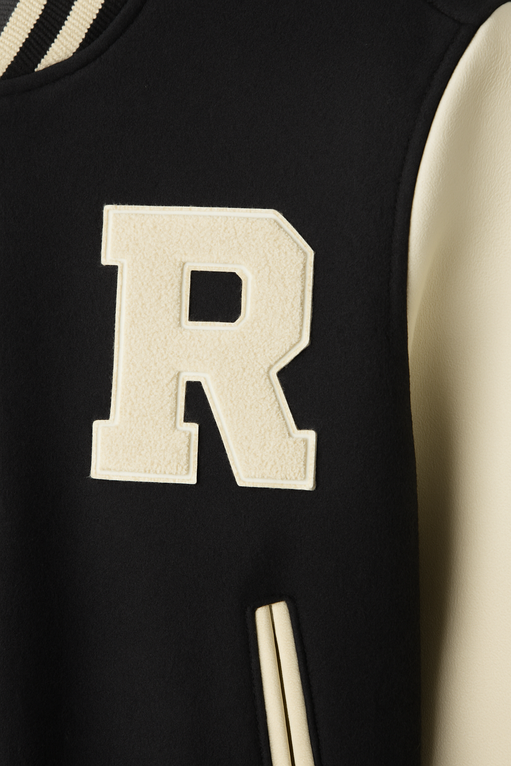 CHAQUETA UNIVERSITARIA LLANA, MANGAS DE CUERO, CUELLO REDONDO CON LINEA NEGRA Y BOTONES A PRESIÓN
