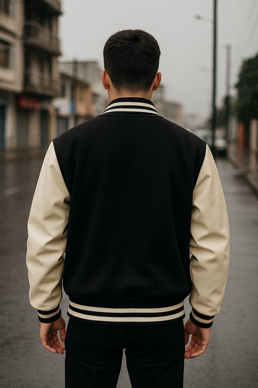 CHAQUETA UNIVERSITARIA LLANA, MANGAS DE CUERO, CUELLO REDONDO CON LINEA NEGRA Y BOTONES A PRESIÓN
