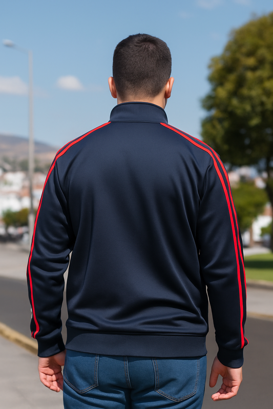 CHAQUETA CON ADORNO METÁLICO, ABERTURA DE CIERRE CON BORDES ROJOS. LINEAS VERTICALES EN BRAZOS